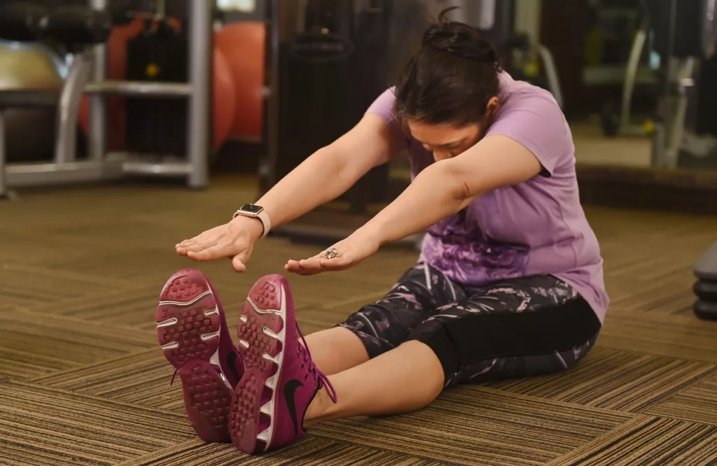 This is a photo of a woman dressed for the gym and performing a floor stretching move